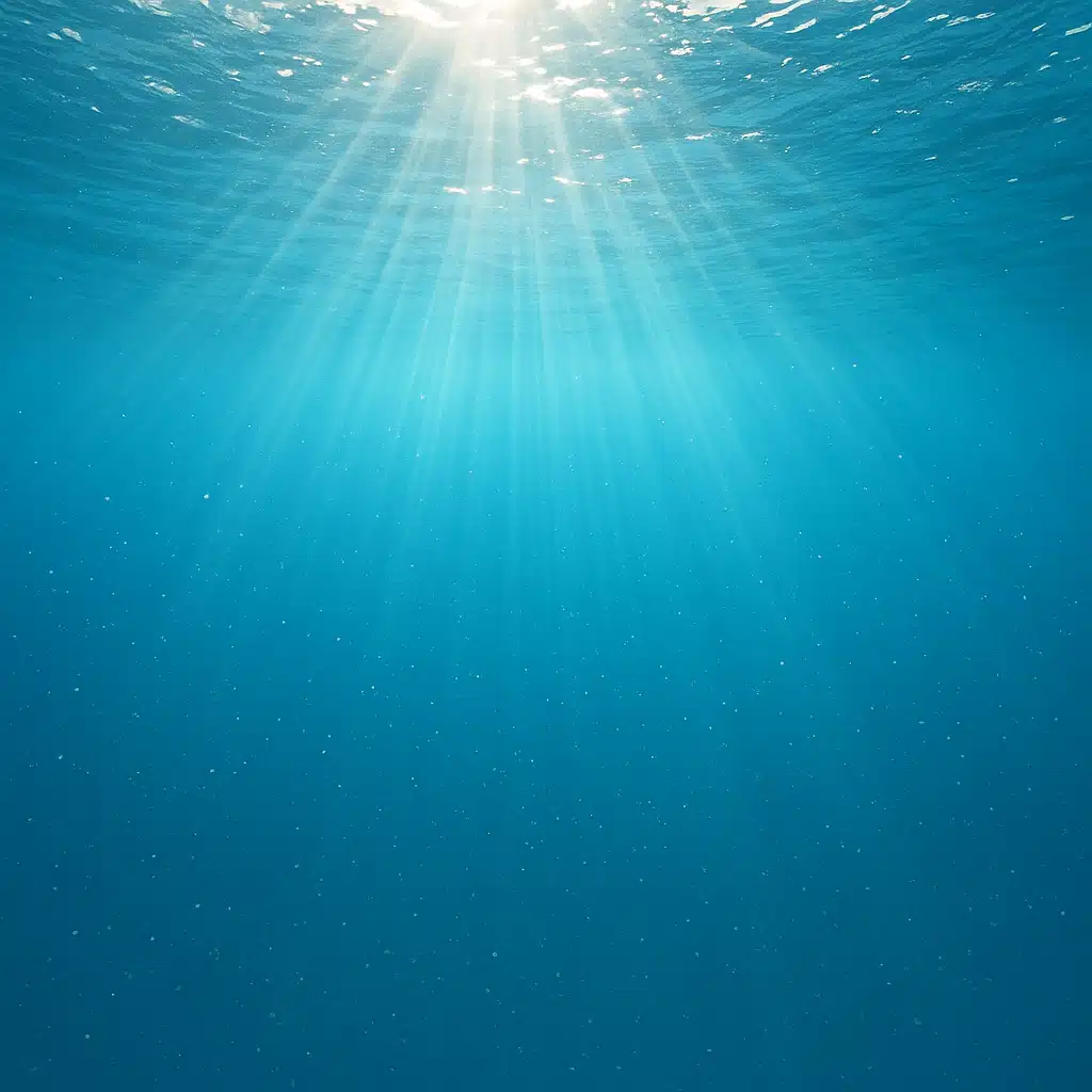 Underwater view of sunlight filtering through clear blue ocean water with visible mineral particles, serene aquatic environment